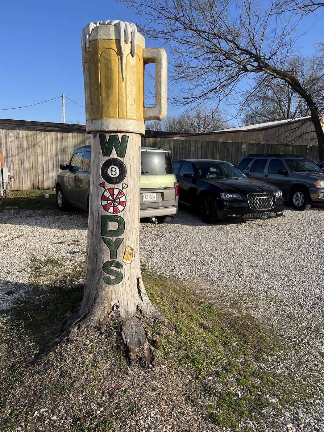 The carved beer mug sign post in the parking lot on a clear winter day